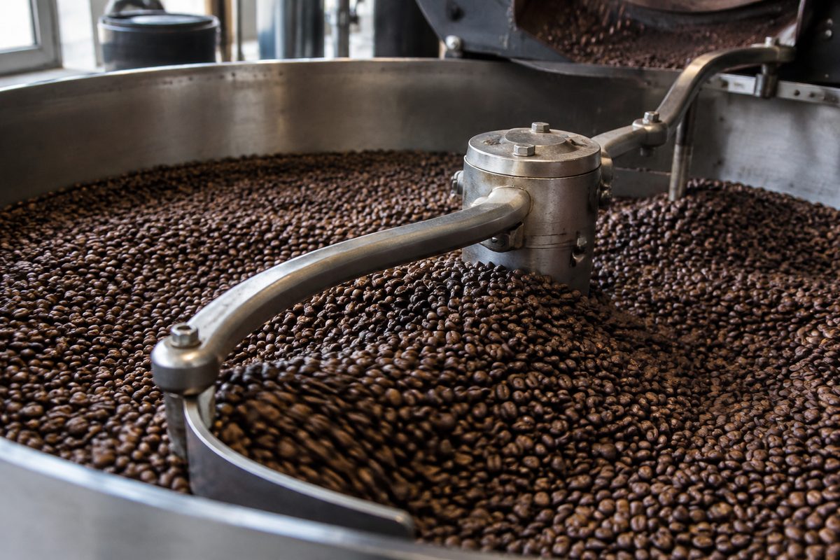 Detail of stainless steel sweep arms gently stirring roasted beans over vacuum cooling screen