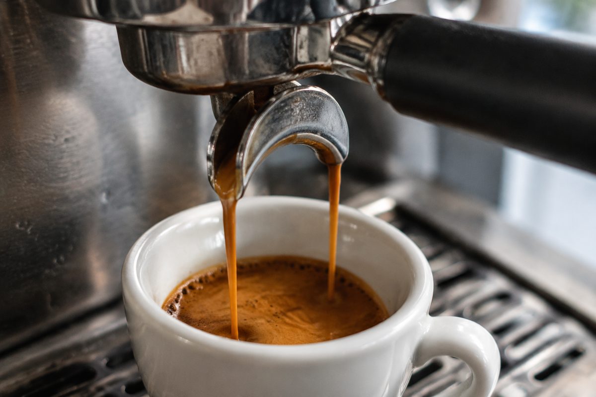 Thick hazelnut crema pouring from a commercial portafilter during an espresso extraction test.