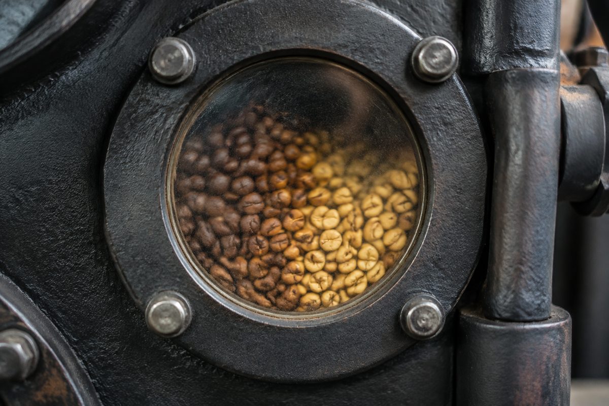 Coffee beans turning pale yellow inside the rotating drum during the endothermic drying phase.